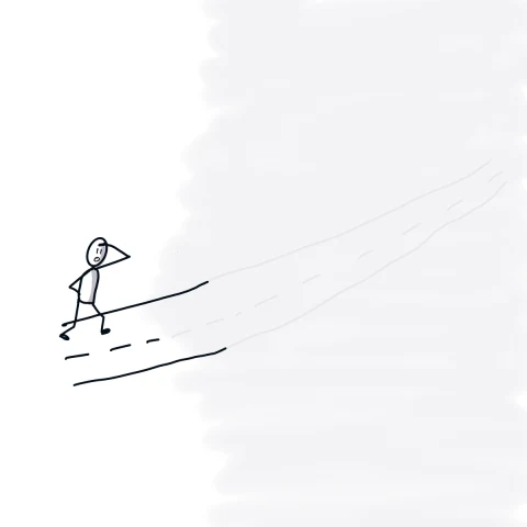 A person faces a road disappearing into fog